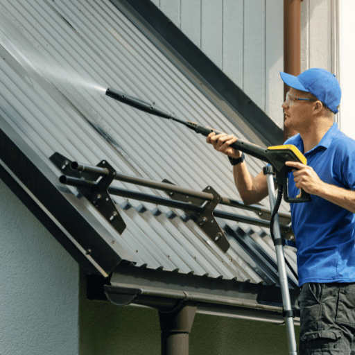 roof cleaning services - technician using pressure washer to clean metal roof